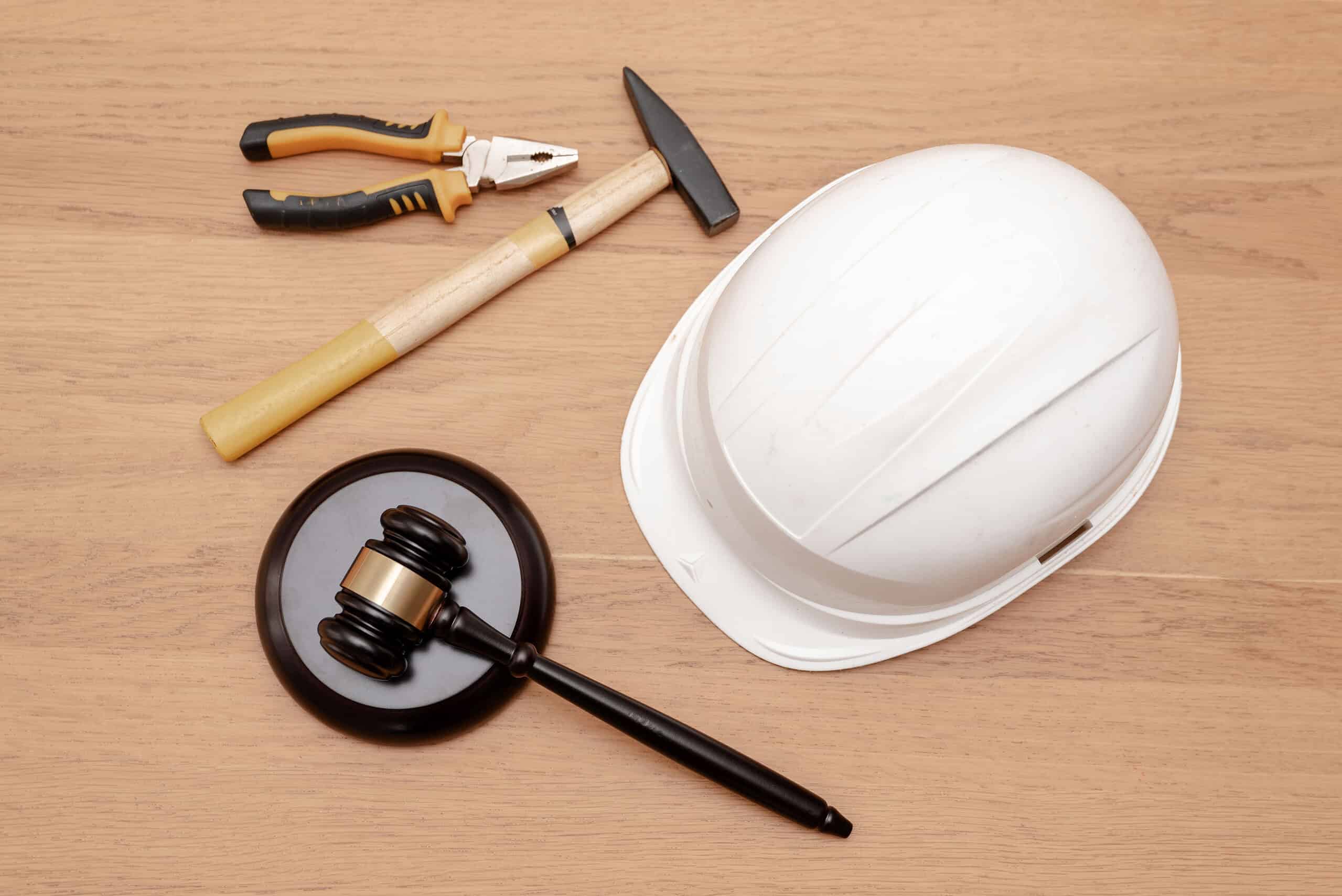 top view of Justice Gavel with white hard hat and industrial tools on wooden background, Construction law concept